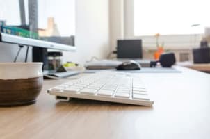 Image of a white keyboard on a wooden desk.