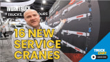 Man standing and talking in front of a trade show wall showing different models of cranes with logos for Work Truck and Truck Chat and headline 16 New Service Cranes.