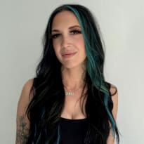 A young woman with long black and green hair, in a black crop top.