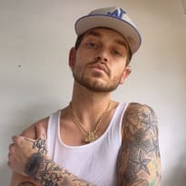 a man with tattoos and a baseball cap