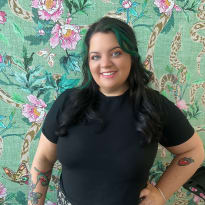 a woman standing against a green floral background