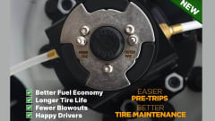 Close-up of a FlowBelow wheel cover center hub with labeled inner and outer tire valve connections and air lines attached, highlighting centralized access for tire inflation and pressure checks.