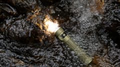 flashlight turn un and submerged in puddle with rain falling.