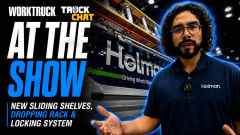Holman representative standing in front of a commercial work van display at a trade show while discussing new van upfit products, including sliding shelves, ladder rack systems, and locking solutions.