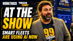 A promotional thumbnail for a Work Truck “Truck Chat” interview filmed at a fleet industry trade show. Large text reads “AT THE SHOW” and “SMART FLEETS ARE USING AI NOW.” A man in a blazer stands in front of an RTA fleet management software booth, speaking about AI and fleet operations.