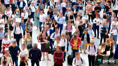 Overhead view of a crowded public space with AI-generated boxes obscuring faces, illustrating automated facial anonymization and privacy protection in video surveillance. Pimloc logo appears in the lower-right corner.
