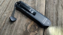 Streamlight Wedge XT compact rechargeable EDC flashlight with pocket clip and wrist lanyard rests on a weathered wooden tabletop, highlighting its slim profile and rugged design.
