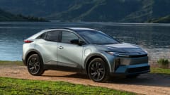 Silver 2027 Toyota C-HR battery-electric SUV parked beside a lake with mountains in the background.