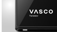 Close-up of a black Vasco Translator device displaying the white Vasco logo and “Translator” text on its screen.