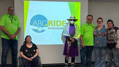 ABQ RIDE Transit Ambassadors pose in front of a projector screen.