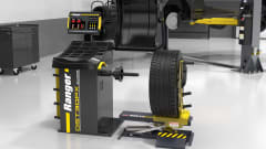 Ranger wheel balancer and pneumatic wheel lift installed in a vehicle service shop next to an SUV on a lift.