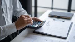 man sitting at desk using a calculator