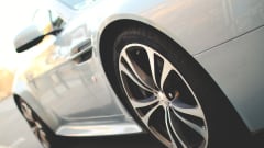 Closeup photo of a new white car on a road from the driver's side 