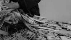 Photo of person grabbing stacks of cash from a surface
