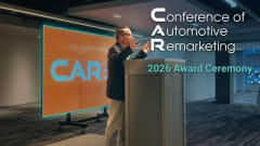 Chris Brown standing on stage at The Conference of Automotive Remarketing announcing this year's award winners. 