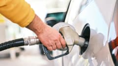 Man's hand holding gas pump in fuel tank of white car