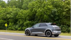 Photo of Ioniq 5 SUV moving on two-lane road next to treeline