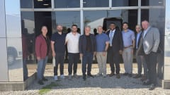 Group photo of men outside storefront.