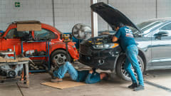Two men do mechanical work on car.