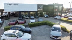 Photo of the exterior of a recently purchased Mazda car dealership with cars for sale parked in front