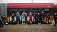 County and agency officials break ground in front of a red and yellow King County Metro public transit bus.