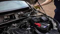 Arm of mechanice reaching for car with hood open