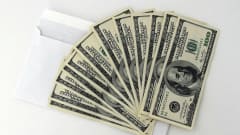 A fan of $100 bills sitting on a white envelope
