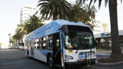 A blue and white OCTA public transit bus parked in the street.