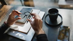 Photo of businessman's hands holding eyeglasses at a desk