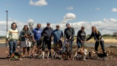 EV drivers posing with rescued dogs on leashes.
