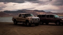 outside shot of two trucks in front of a body of water with a cloudy sky