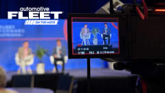 A camera monitor shot of two people on a conference stage. 