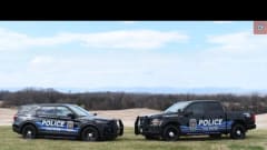 Two Culpeper Police vehicles, an SUV and pickup, display a new Blue Ridge Mountain-inspired design while parked on grass with a scenic landscape in the background.