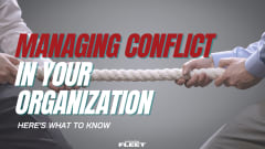 Two employees pull opposite ends of a rope in a tug-of-war, illustrating workplace conflict and the leadership strategies fleet organizations use to improve communication and teamwork.