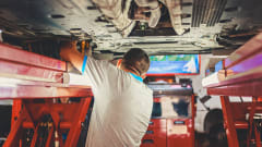 man performing maintenance under a car 