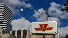 A vintage TTC sign against a blue cloudy sky.