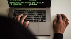 Person at laptop with green-colored code on the screen