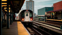 A subway train arriving at a Bronx station in New York City during the day.