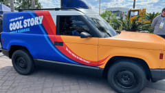 A side view of the yellow, blue, and red Slate Auto electric pick-up truck and SUV