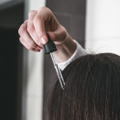 the rear view of a head of hair, having serum dropped onto the scalp.
