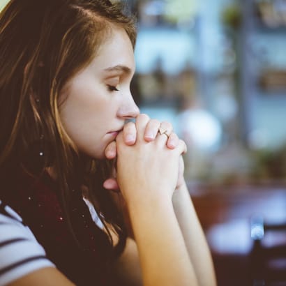 A woman with her eyes closed and hands clasped