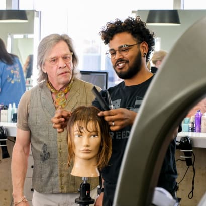 Educator Oscar Bond evaluates a student's haircut on a mannequin.