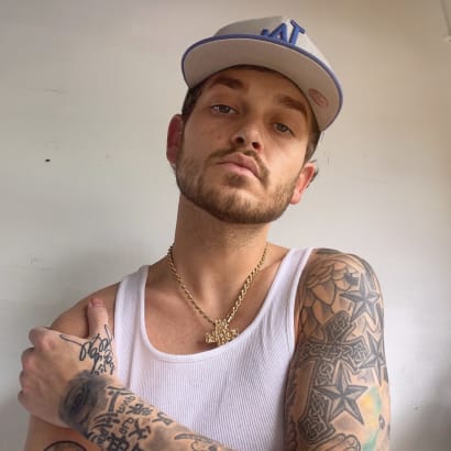 a man with tattoos and a baseball cap