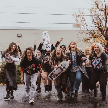 With skate boards in hand, a group of stylists playfully charge the photographer.