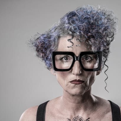 Older woman with big black glasses and short curly hair