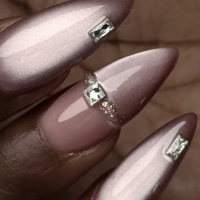 Three fingernails with long pink nails and faux diamonds