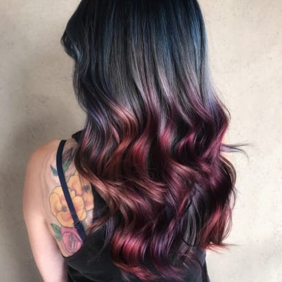 A brunette woman with pieces of bright color throughout her hair.