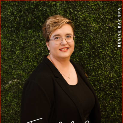 A photo of a woman in black against a green wall.