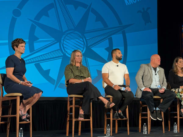 Five panelists deliver a seminar on stage. 