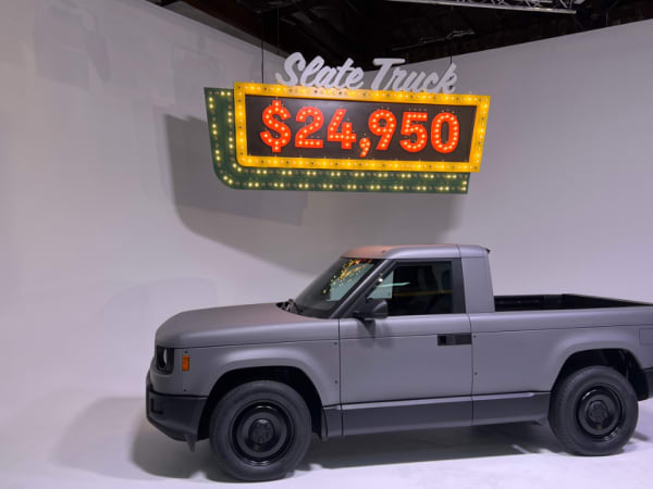 Slate pickup truck in front of a neon lit price-tag sign